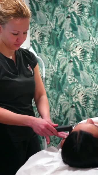 臨床でストレッチャーに横たわっている患者の肩の痛みを治療するインディバツールを使用した専門知識の垂直写真 — ストック動画
