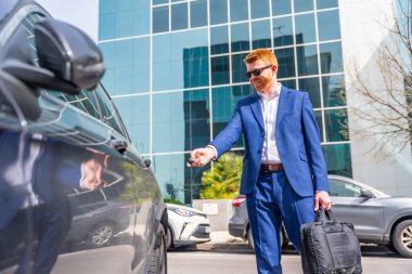 Havalı iş adamı şehirde uzaktan kumandalı siyah bir araba açıyor.