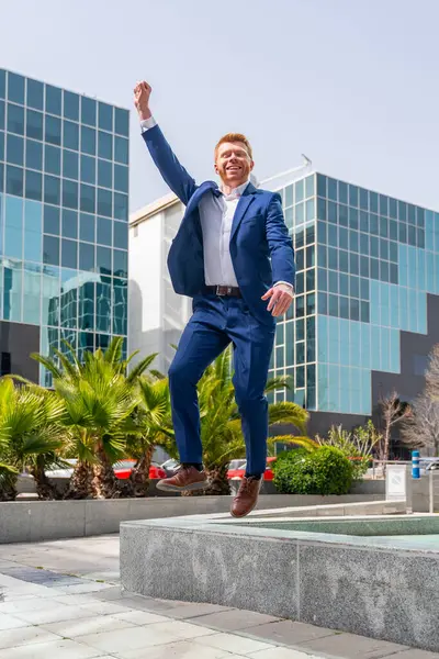 一个成功的商人跳起来庆祝在城市的胳膊的垂直照片 免版税图库图片