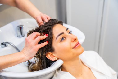 Kuaför saçını kuaförde yıkarken lavaboya yaslanan güzel bir kadının yakın çekimi.