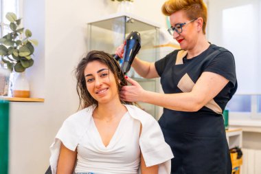 Kuaförde saçlarını kuruturken gülümseyen beyaz saçlı güzel kadın.