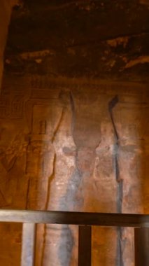 Ebu Simbel Tapınağı 'nın aydınlanmış iç mekanını ve onun değerli hiyerogliflerini ziyaret eden genç bir kadın Nubia' da, Nasser Gölü 'nün yanında. Firavun 2. Ramses Tapınağı, 4k video.