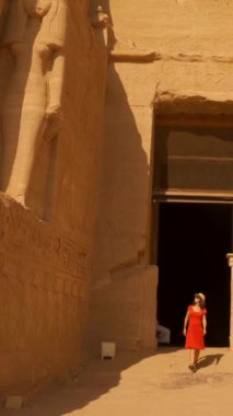 Ebu Simbel 'in güzel tapınağından firavunlar görünene kadar çıkan genç bir kadın Nubia' da Nasser Gölü 'nün yanında. Firavun 2. Ramses Tapınağı, 4k video.