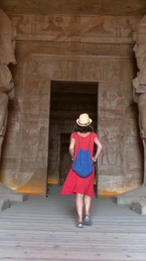 Genç bir turist, Mısır 'ın güneyindeki Abu Simbel tapınağında Nasser Gölü' nün yanındaki heykelleri ziyaret ediyor. Firavun 2. Ramss Tapınağı, 4k video