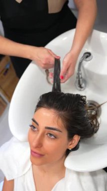 Kuaför saçını kuaförde yıkarken lavaboya yaslanan güzel bir kadının yakın çekimi.