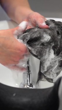 Tanımlanamayan beyaz bir kadın kuaförün şampuanla temizlediği doğal kılcal protez.