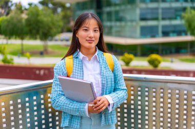 Üniversitenin önünde gururla duran Asyalı güzel bir kızın çeyrek boyunda portresi.