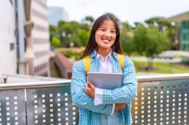Şirin Çinli üniversite öğrencisi kampüsün dışında kameraya gülümsüyor.