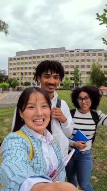 Üç havalı çoklu etnik öğrenci giyilebilir kamera ve tripodla selfie çekiyorlar.