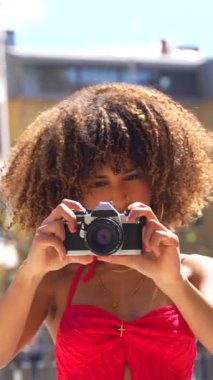 Vertical video with copy space of a beauty brunette female tourist taking photos with a camera while visiting a city