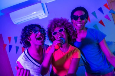 Mutlu çoklu etnik arkadaşlar geceleri karaoke söyleyip apartmanda parti yapıyorlar.