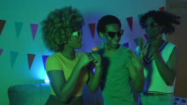Arkadaşların geceleri şarkı söyleyip karaoke yaparken mavi neon ışıkları oturma odasını aydınlatıyor.