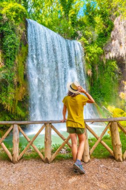 İspanya, Aragon 'daki Piedra Manastırı' ndaki La Caprichosa şelalesine bakan şapkalı bir turist kadın.