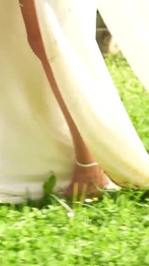 Gelinin düğün günü çimlerde yürümesinin ayrıntıları.