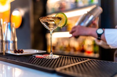 Tanınmayan bir barmen gece kulübünde martini bardağında lüks bir kokteyl hazırlıyor.