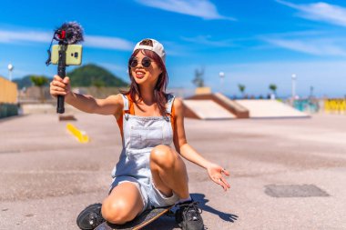 Çinli genç bayan flamalı kaykay parkında internetten kayıt yapıyor.