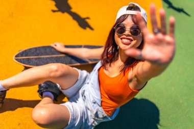 Yüzü kaykay parkında el kapaklı el kol hareketi yapan gülümseyen Çinli bir kadının en iyi görüntüsü.