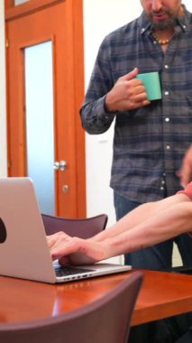 Özürlü beyaz bir adam ve birlikte çalışma sürecinde dizüstü bilgisayar kullanan bir iş arkadaşı.