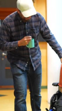 Serebral felçli bir adam mesai arasında iş arkadaşının yanında gülerek otomatlara giriyor.