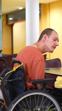 Yetişkin, beyaz ve sıradan bir adam iş yerinde çalışan bir kafeteryada bir meslektaşını engelli ile besliyor.