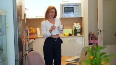 Sarışın, beyaz, yetişkin bir iş kadını kahve molası sırasında cep telefonunu kontrol ediyor.