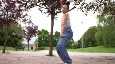 Mavi kotlu ve beyaz gömlekli bir kadın beton zeminde dans ediyor. Özgürlük ve neşe kavramı, çünkü kadın tamamen dansla meşgul.