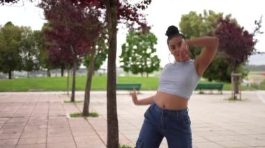 Mavi kotlu ve beyaz gömlekli bir kadın beton zeminde dans ediyor. Özgürlük ve neşe kavramı, çünkü kadın tamamen dansla meşgul.