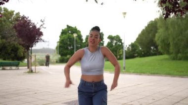 Mavi kotlu ve beyaz gömlekli bir kadın beton zeminde dans ediyor. Özgürlük ve neşe kavramı, çünkü kadın tamamen dansla meşgul.