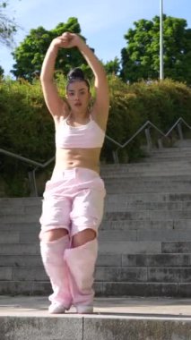 Pembe pantolonlu bir kadın merdivenlerde dans ediyor. Özgürlük ve neşe kavramı, çünkü kadın tamamen dansla meşgul.