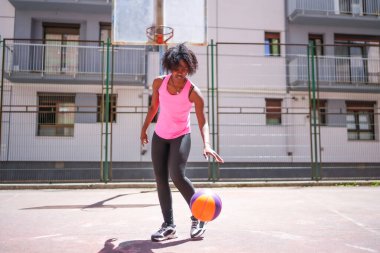 Şehir mahkemesinde basketbol oynayan Afro-Amerikan bir genç kızın tam boy fotoğrafı.
