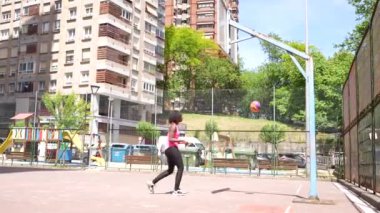 Genç Afrikalı Amerikalı bayan basketbolcu şehir basketbol sahasında çalışıyor.