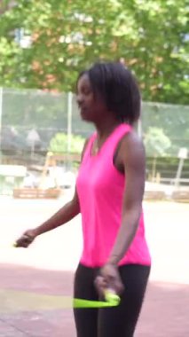 Genç bir Afrikalı Amerikalı kadının şehir basketbol sahasında esneme hareketlerini gösteren uzun bir video.