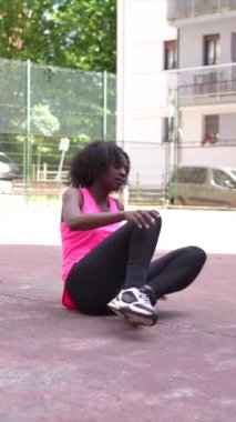 Genç bir Afrikalı Amerikalı kadının şehir basketbol sahasında esneme hareketlerini gösteren uzun bir video.