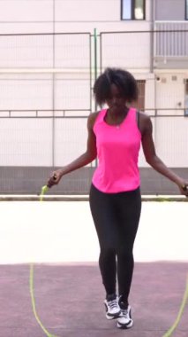 Afro-Amerikan bayan basketbolcunun açık hava tesislerinde antrenman yaptığı dikey bir video.
