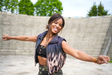 Neşeli gülümseyen Kübalı genç ve güzel bir kadın parkta salsa yapıyor.