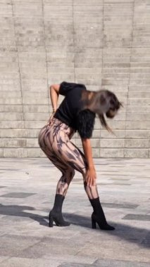 Bir kadının parkta dans eden şehvetli Latin müziğini çevirdiği dikey bir video.