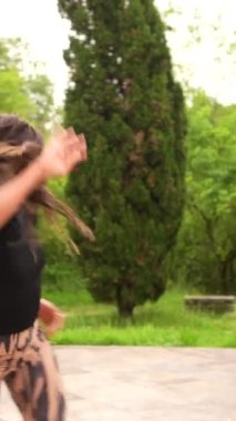 Halk parkında salsa yapan İspanyol bir kadının dikey videosu.