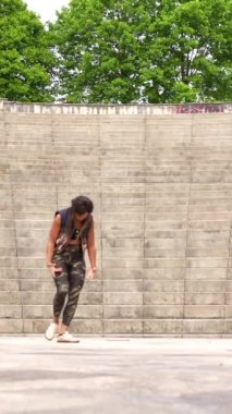 Kübalı bir kadının parkta tek başına salsa yaptığını gösteren dikey bir video.