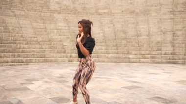 Parkta Küba salsası yaparken yukarı bakan güzel Latin bir kadının düşük açılı görüntüsü.