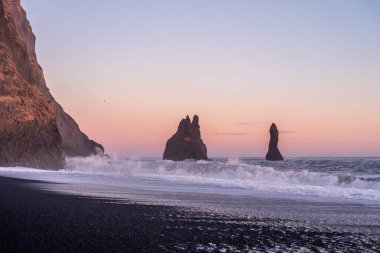 Reynisfjara 'nın kara kumsalında volkanik oluşumlar İzlanda' da gün batımında