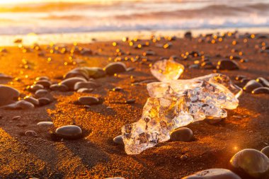 Güneş doğarken buz ve taşlar İzlanda 'da Jokulsarlon' un yanındaki elmas plajında.