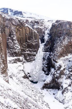 Hengifoss waterfall frozen in the cold winter of Iceland clipart