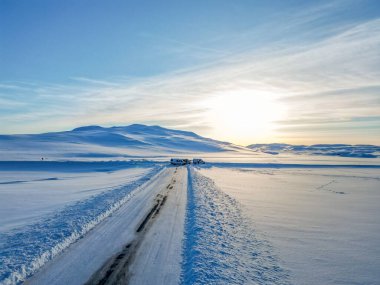 Hava aracı görüntüsü. İzlanda 'da kışın donmuş yol. Kış boyunca yol kenarlarında mavi gökyüzü.