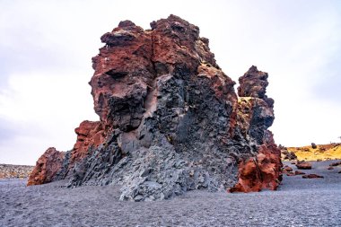 Red rock formations at Djupalonssandur beach on the Snaefellsnes peninsula in winter in Iceland clipart