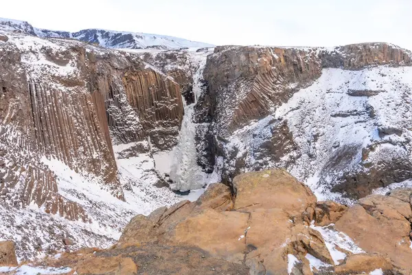 Hengifoss waterfall frozen in the cold winter of Iceland, volcanic cliffs