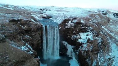 Skogafoss şelalesinin karlı ve kışın İzlanda 'da bol miktarda suyu olan insansız hava görüntüsü.