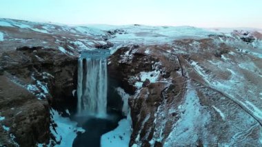 Skogafoss şelalesinin karlı ve kışın İzlanda 'da bol miktarda suyu olan insansız hava görüntüsü.