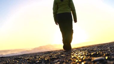 Kışın İzlanda 'nın Reynisfjara plajında yürüyen ve pilates yapan bir kadın.