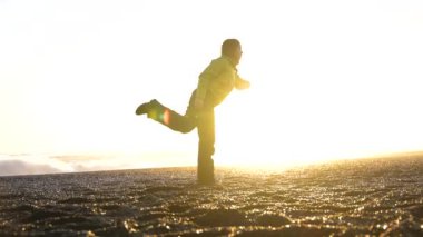 Kışın İzlanda 'da Reynisfjara' nın güzel kumsalında pilates yapan bir kadın.