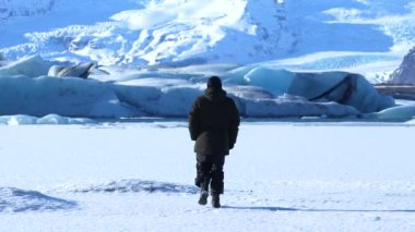 İzlanda 'da kışın Vatnajokull buzulunda geriye doğru yürüyen maceracı genç adam.